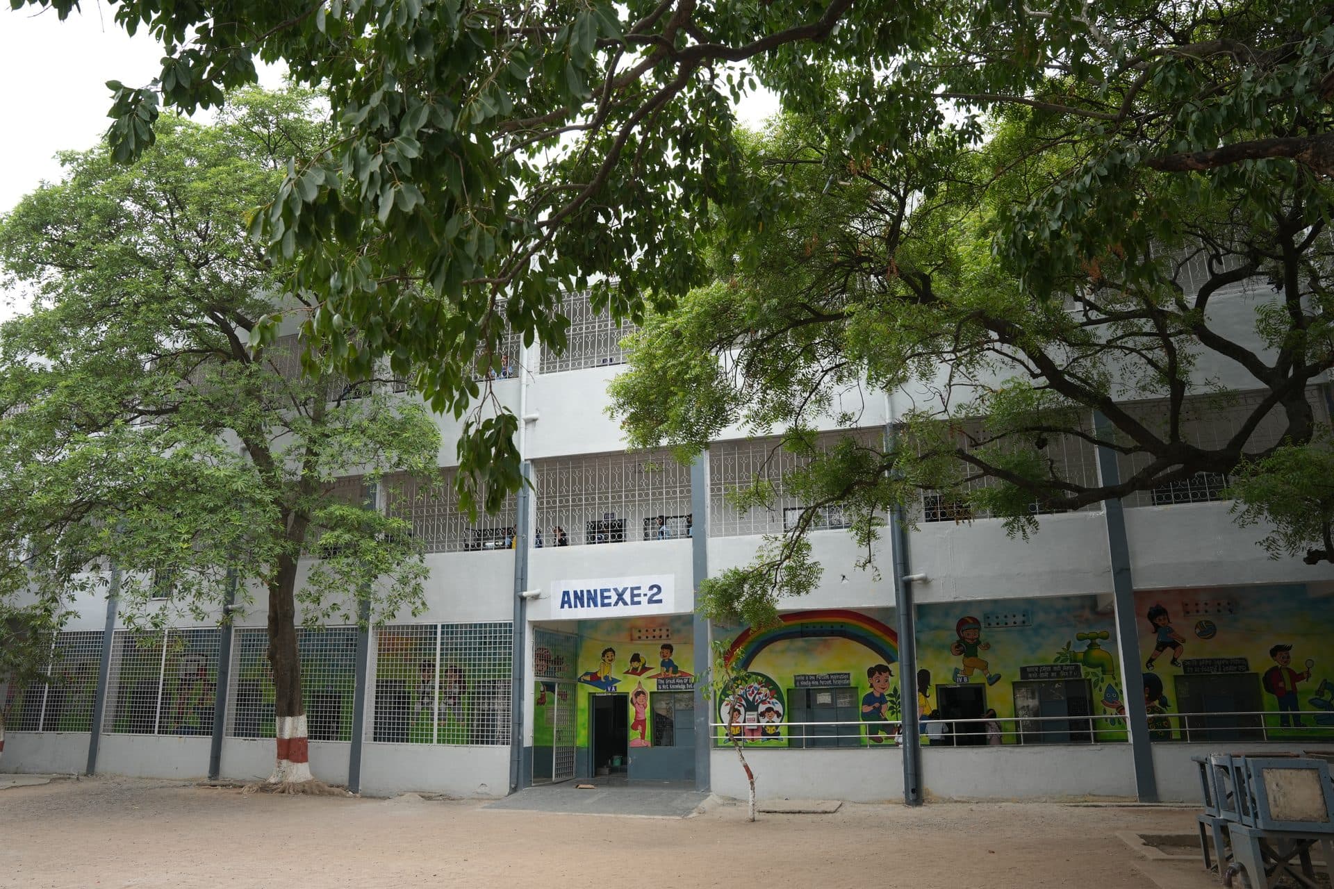 A long classroom annexe with brightly painted educational murals along its length