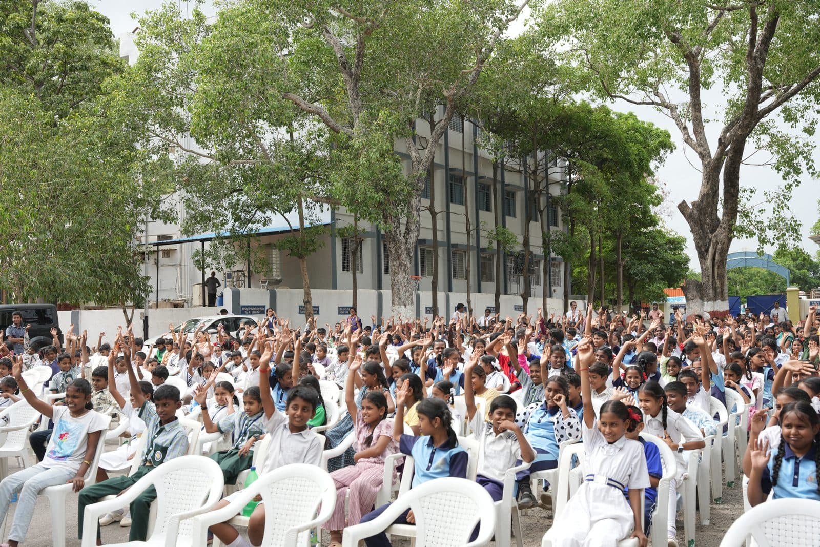 Students in the audience raising their hands enthusiastically during a programme