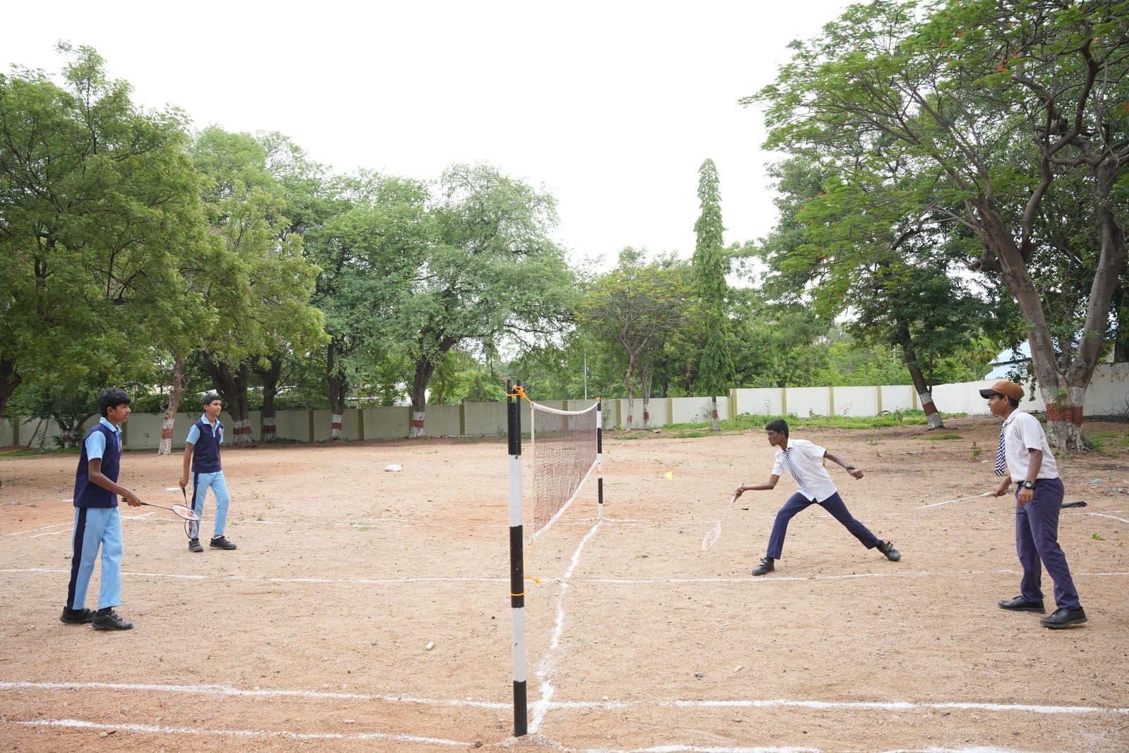 Students playing badminton across a net on the school ground