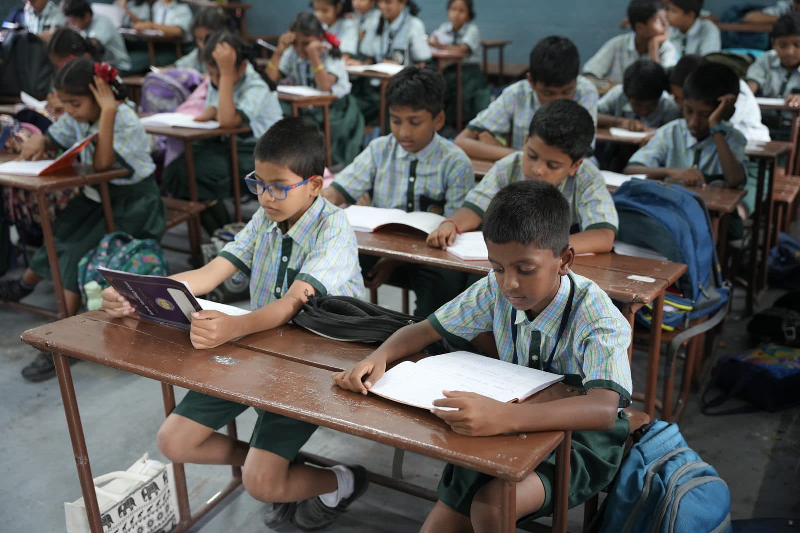 Primary students at their desks reading from workbooks during a lesson