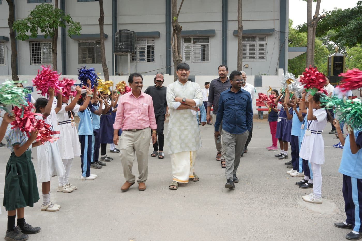 Guests walking between two rows of students holding raised pom-poms
