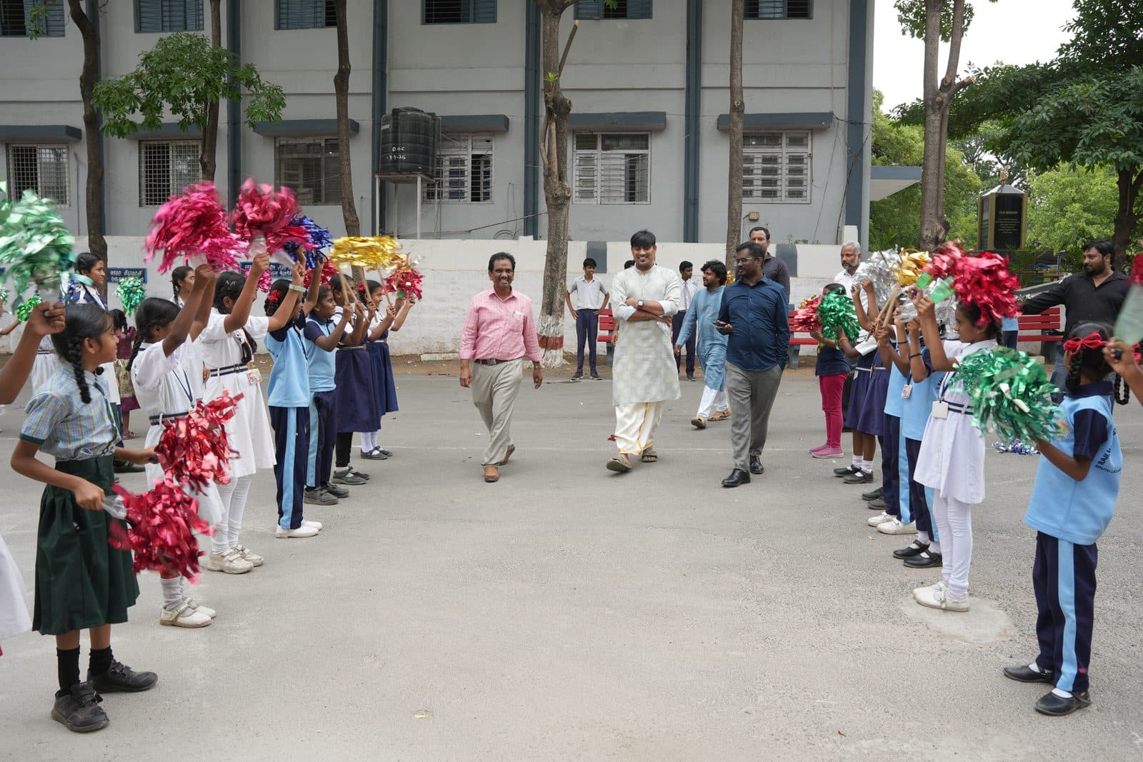 Students lining the path with decorative pom-poms raised to welcome arriving guests