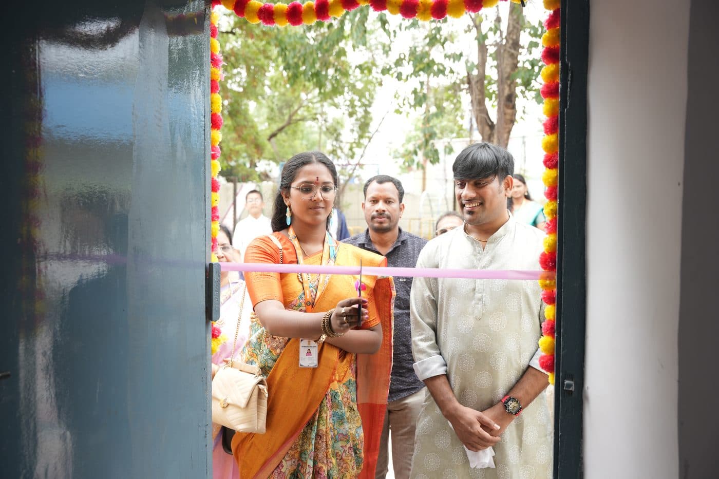 A ribbon being cut at a marigold-decorated doorway during the inauguration