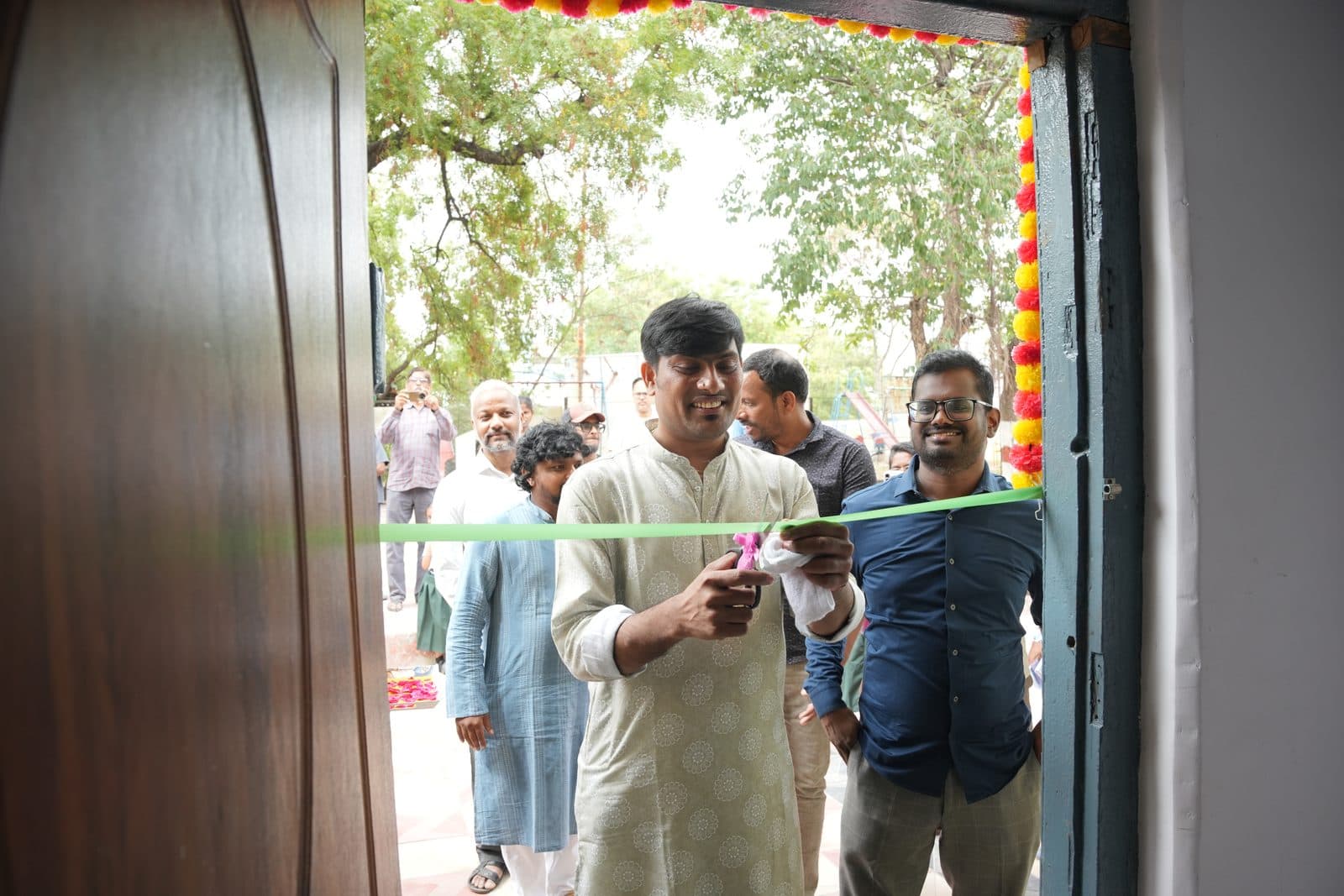 A guest cutting the ribbon at a garland-framed doorway during a block inauguration