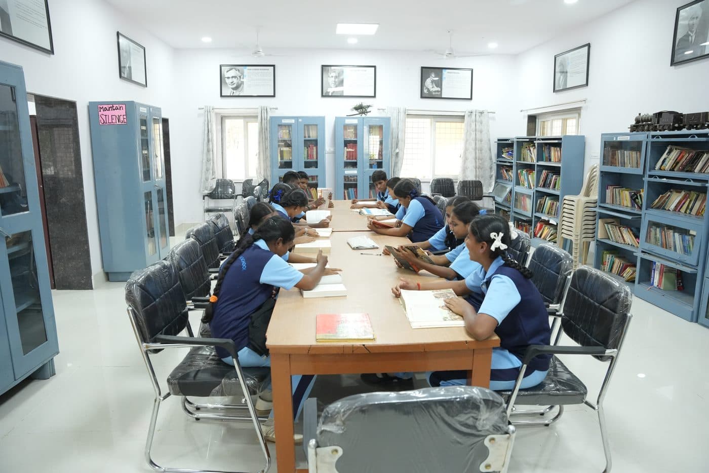 Students turning the pages of books at the library reading table