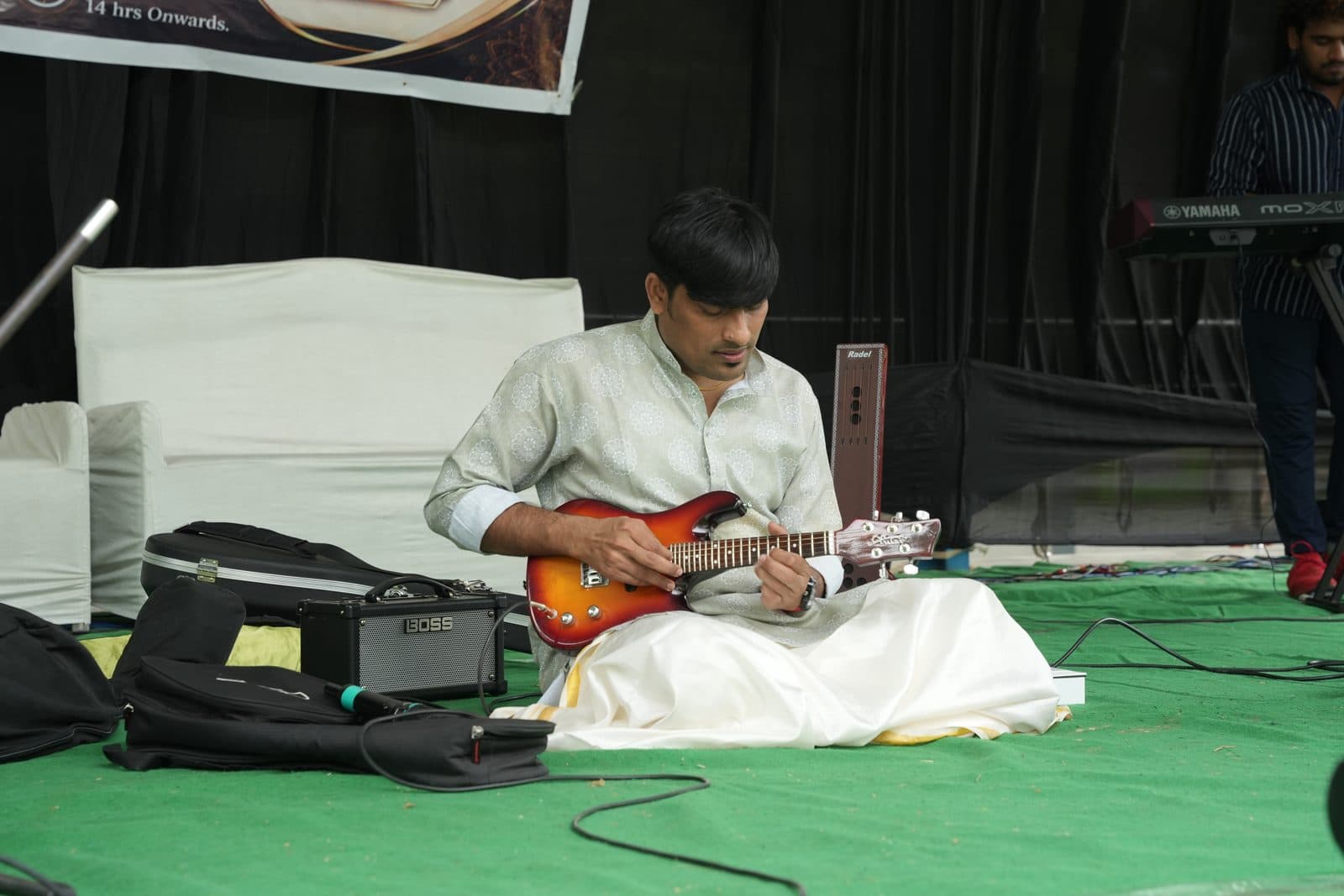 A musician playing the mandolin seated on stage during the cultural programme