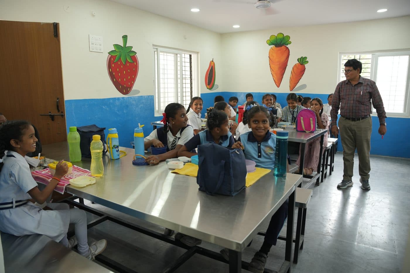 Students at the dining table with water bottles and lunch boxes during the meal break