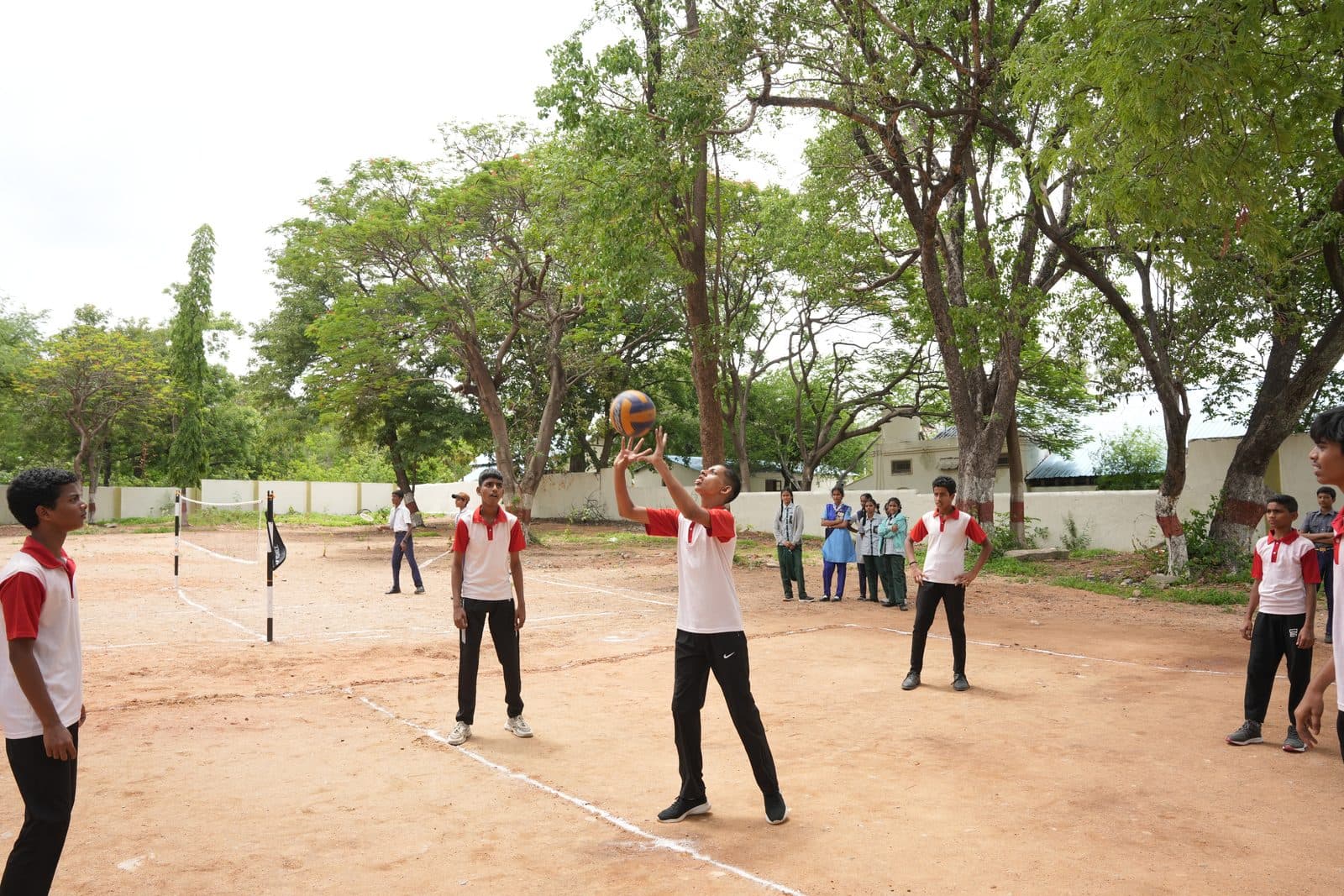Students playing a volleyball match on the outdoor court